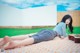 A woman laying on a blanket with a guitar.