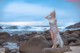 A woman in a white dress standing on a rocky beach.