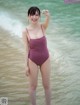 A woman in a purple swimsuit standing in the water.