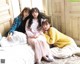 A group of young women sitting on top of a bed.