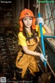 A woman wearing a hard hat and overalls holding a shovel.