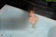 A naked woman is sitting in a bathtub with water.
