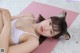 A woman laying on a pink yoga mat wearing a cat ears headband.