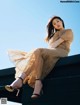 A woman sitting on top of a building wearing a dress.