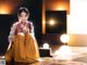 A woman in a yellow kimono sitting on the floor.